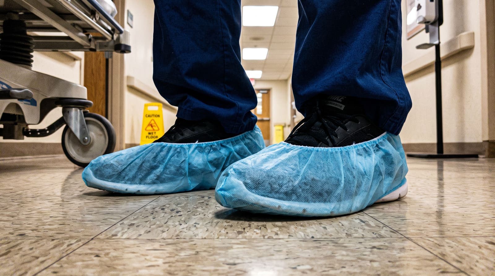 Personnel wearing disposable shoe covers in a commercial facility corridor.